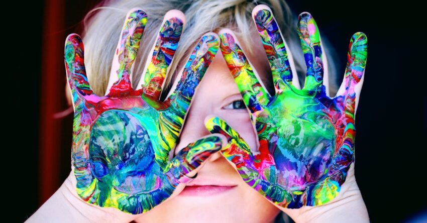 Vibrant close-up of a child's hands covered in colorful paint, expressing creativity and fun.